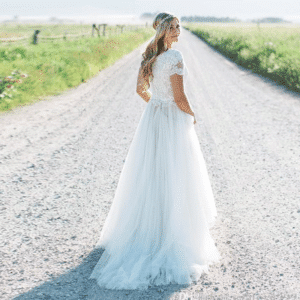 Robe de mariée bohème simple en dentelle apporté par une mannequine dans une route.